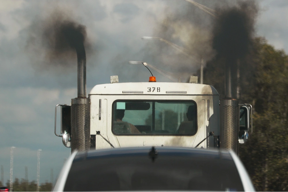 A truck with gas emissions coming from it's tailpipes