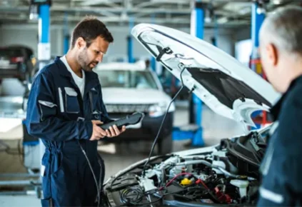 A person opening up the hood of a vehicle holding an onboard diagnostics (OBD) scanner