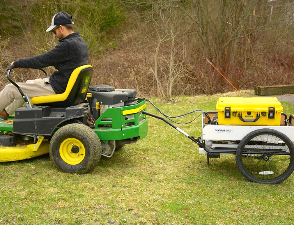 A picture of a person driving an ATV with a PEMS product on a cart in tow