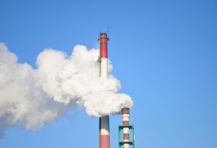A picture of a red and black smoke stack emitting harmful explosive gas into the air