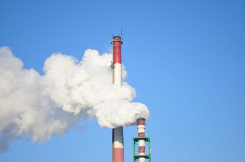 A picture of a red and black smoke stack emitting harmful explosive gas into the air