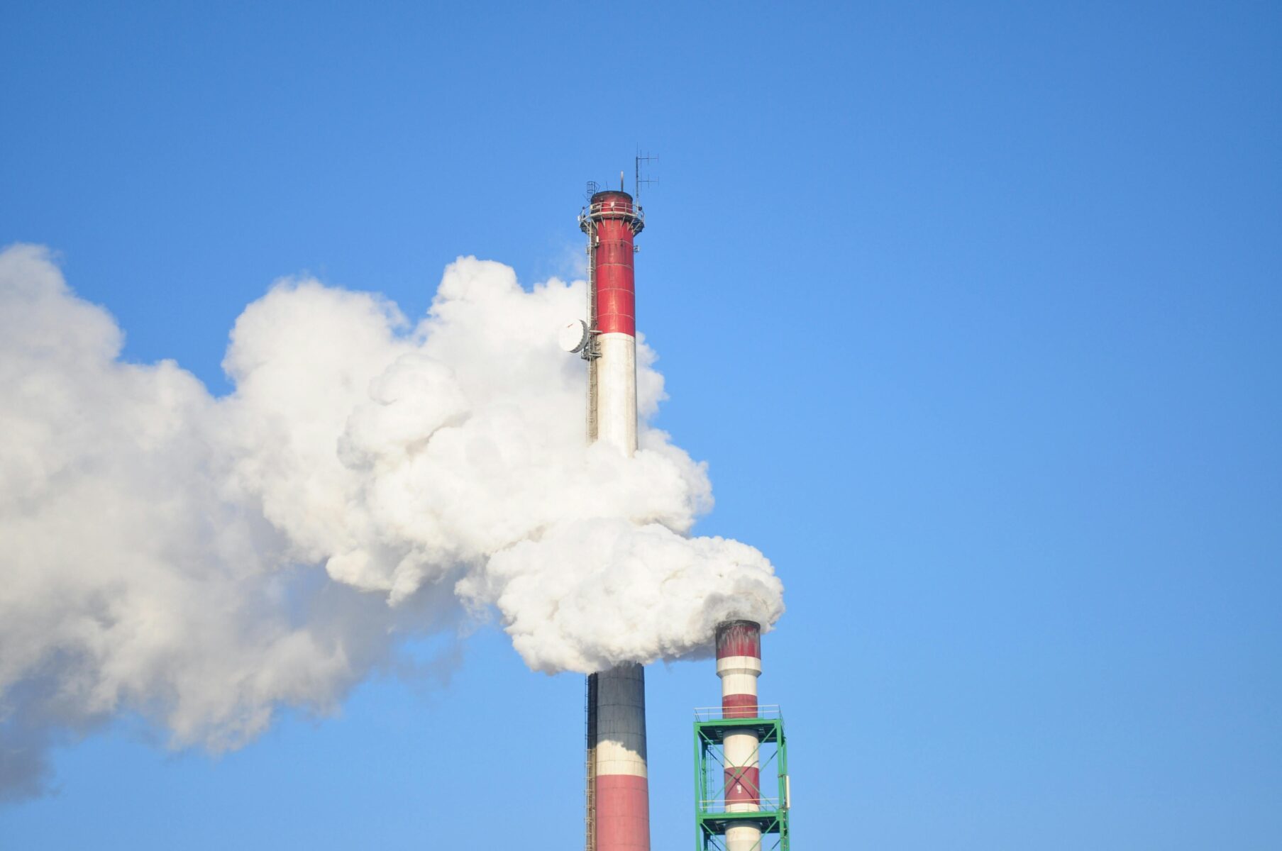 A picture of a red and black smoke stack emitting harmful explosive gas into the air