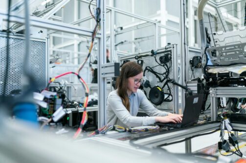 A picture of a woman typing on a computer with a car product to her right