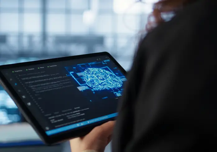 Person analyzing data on a tablet showing a neural network diagram representing AI technology