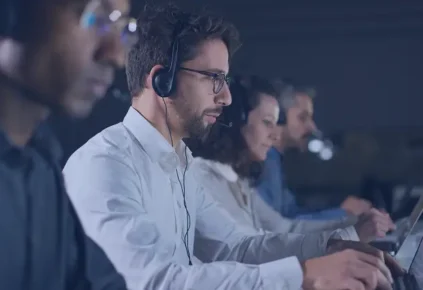 People working on computers with headsets representing customer support in AI technology