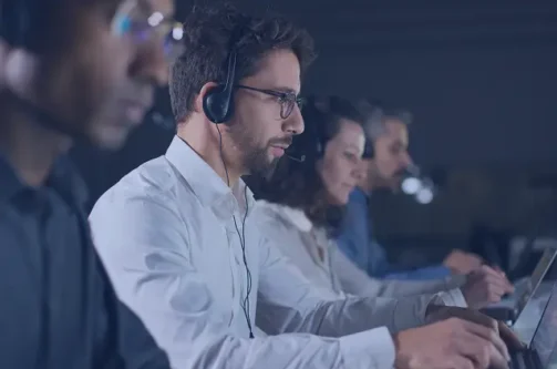 People working on computers with headsets representing customer support in AI technology
