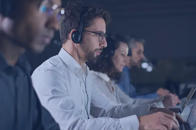 People working on computers with headsets representing customer support in AI technology