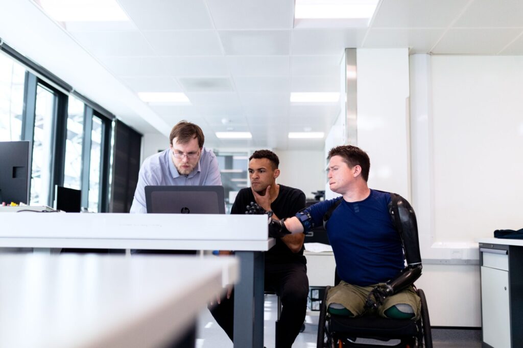 Picture of an engineering team of three staring at a computer screen for a virtual lab